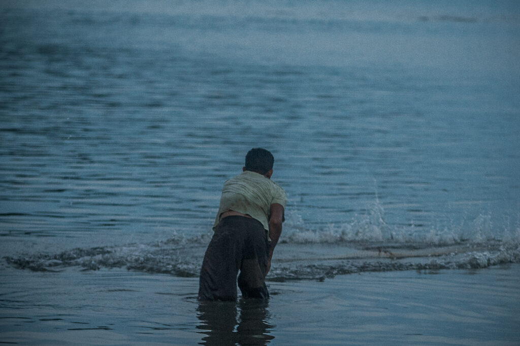 Um homem encurvado na beira do rio