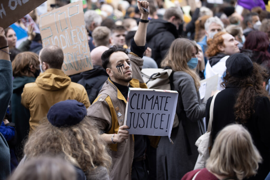 Protesto em Glasgow. Homem com placa Climate Justice, justiça climática