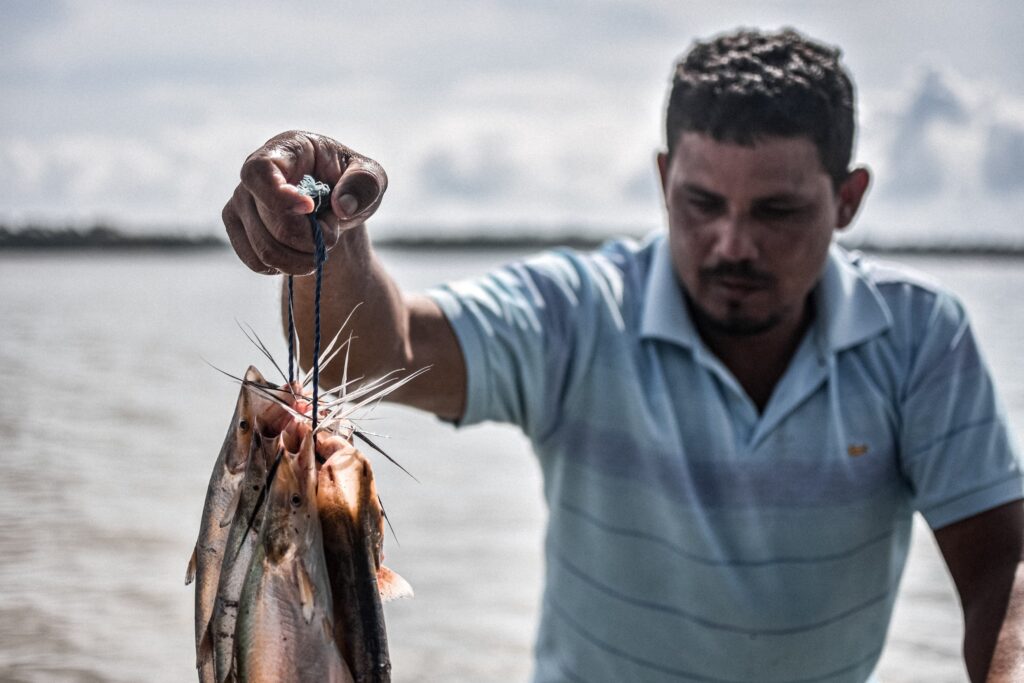 Um pescador segura um peixe com mão direita